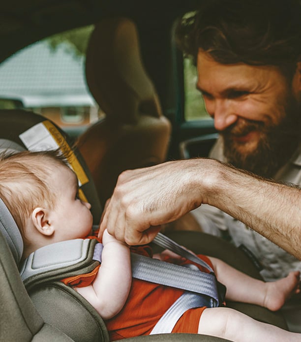 father buckling baby ito car seat