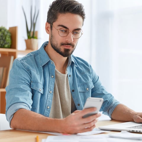 man on working on laptop taking break to look at cellphone-1