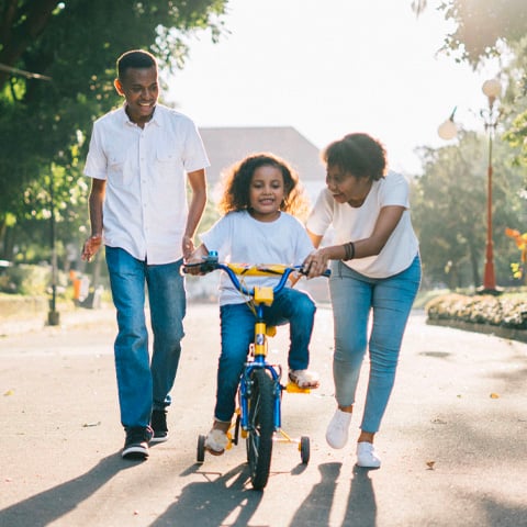 parents teaching daughter how to ride bike