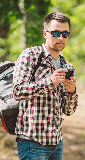 man on hike stopping to use his phone