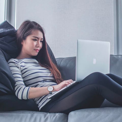 Woman sitting on sofa while on laptop