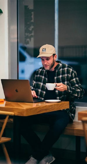 man sitting while having coffee on his laptop