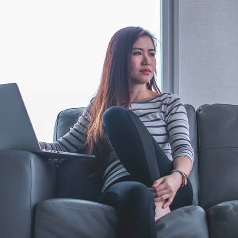 woman sitting on couch using laptop