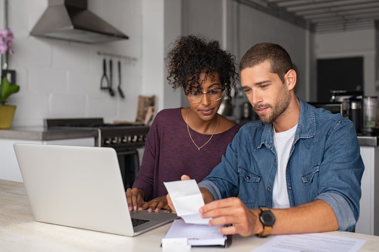 male and female look at bills in front of computer